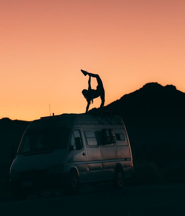 Silhouette of a person in a powerful warrior yoga pose at sunset.